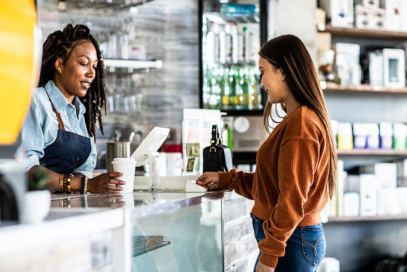 Una mujer compra un café con una tarjeta de débito.