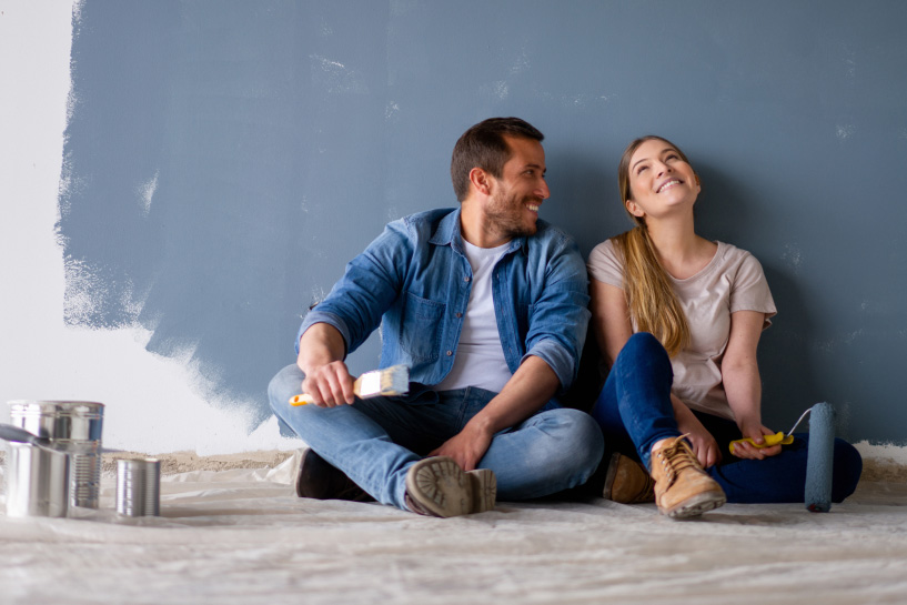 A man and woman take a break from painting their home.