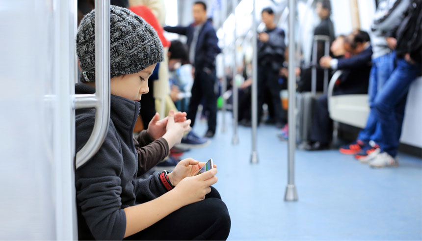 Teenage boy playing the mobile games on his phone in the train