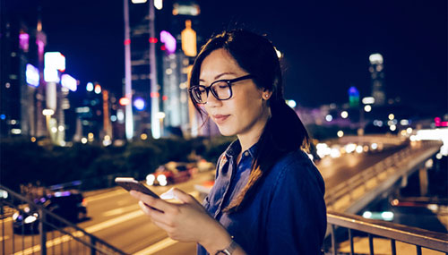 Young Chinese woman using smartphone in the city at night