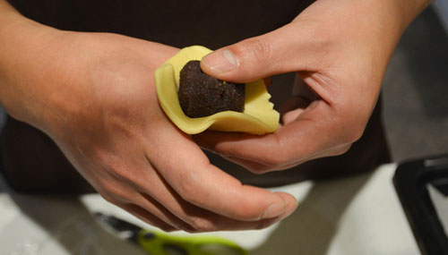 Clarrisa wrapping the dough skin around the mooncake filling